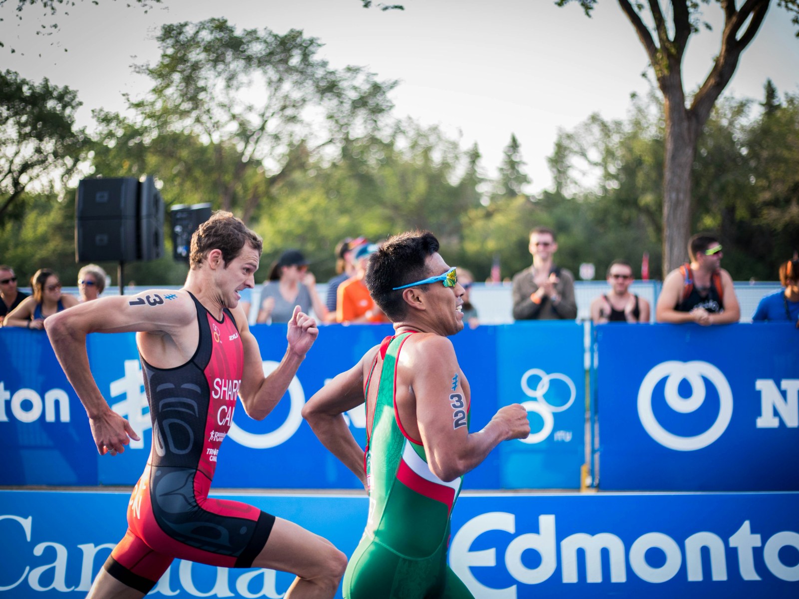 Two triathletes running shoulder to shoulder in a race.